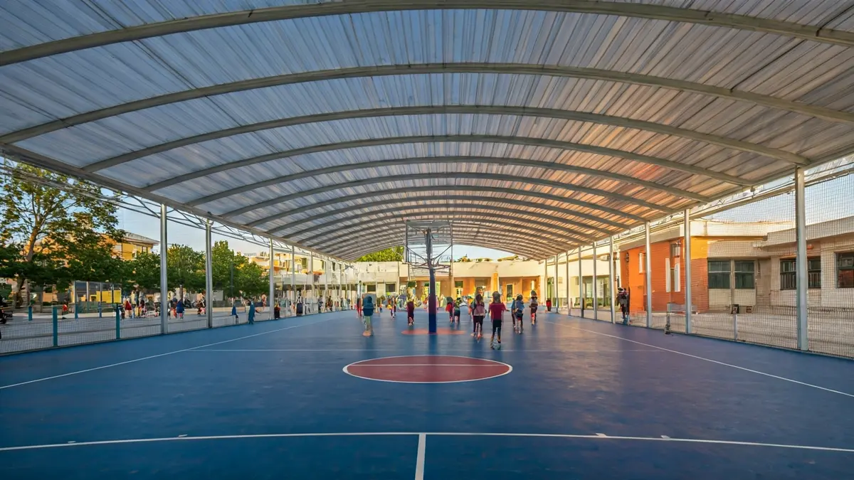 Imatge d'una pista de bàsquet coberta al costat d'una escola.