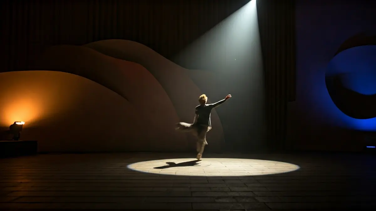 Imagen genérica de un escenario de danza con un bailarín en movimiento y luces teatrales.