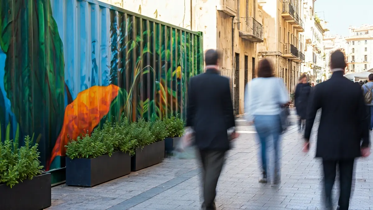 Imagen de un contenedor de poda decorado con murales artísticos en una calle de Dénia, con motivos vegetales y elementos simbólicos de la ciudad.