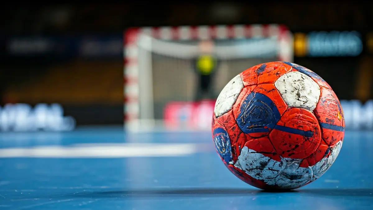 Generic image of a handball on the court, with the goal net blurred in the background.