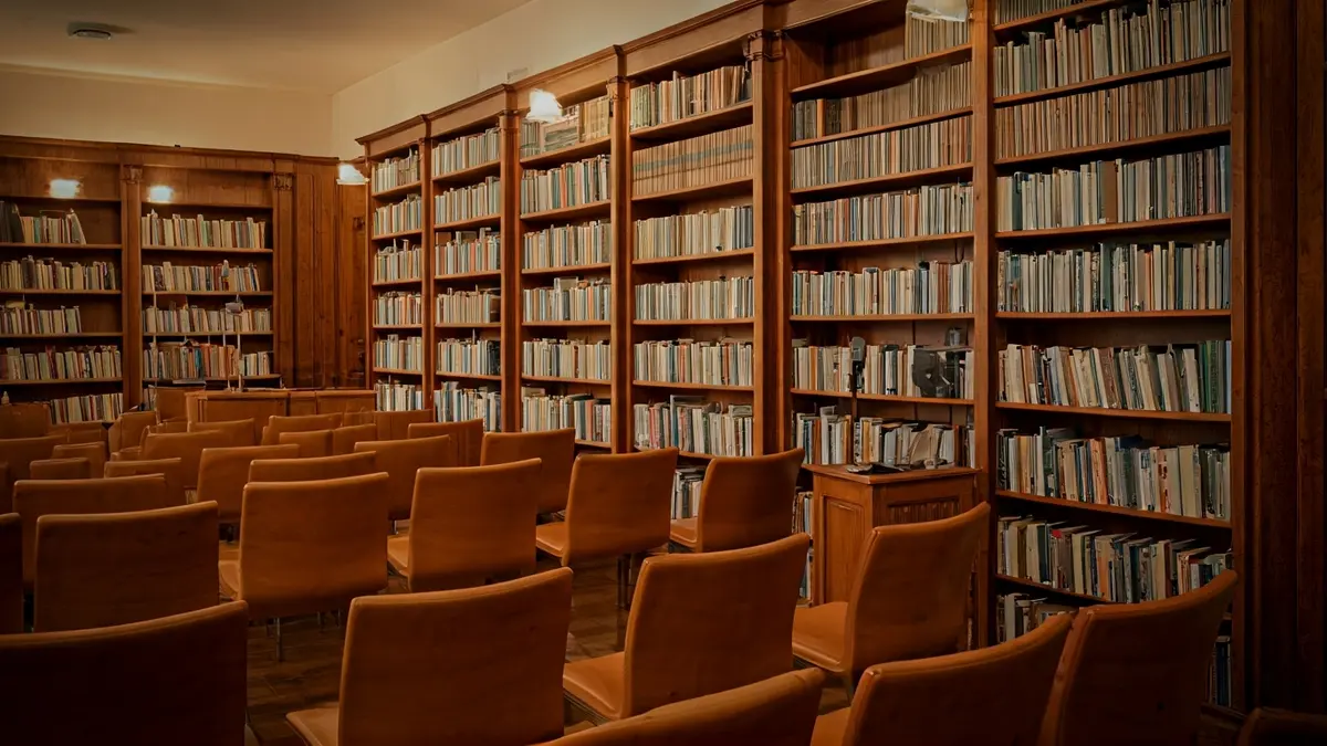 Imagen genérica de una biblioteca con estanterías de madera y un podio con micrófono, con una iluminación cálida.
