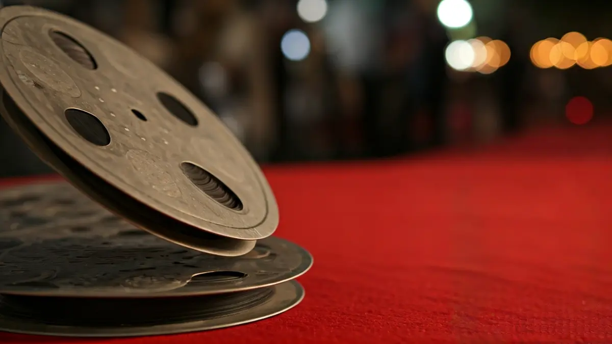 Imatge d'un rodet de pel·lícula amb un fons desenfocat d'una catifa roja, suggerint un festival de cine.