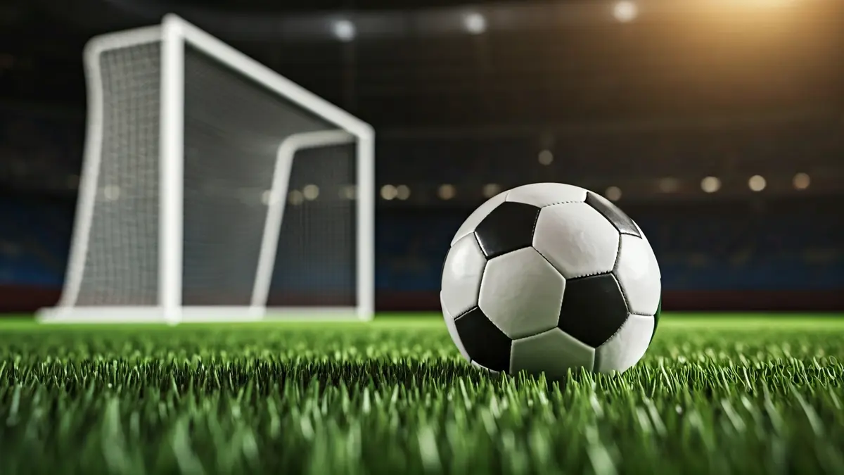 Generic image of a soccer ball on a grass field, with a blurred goal in the background.