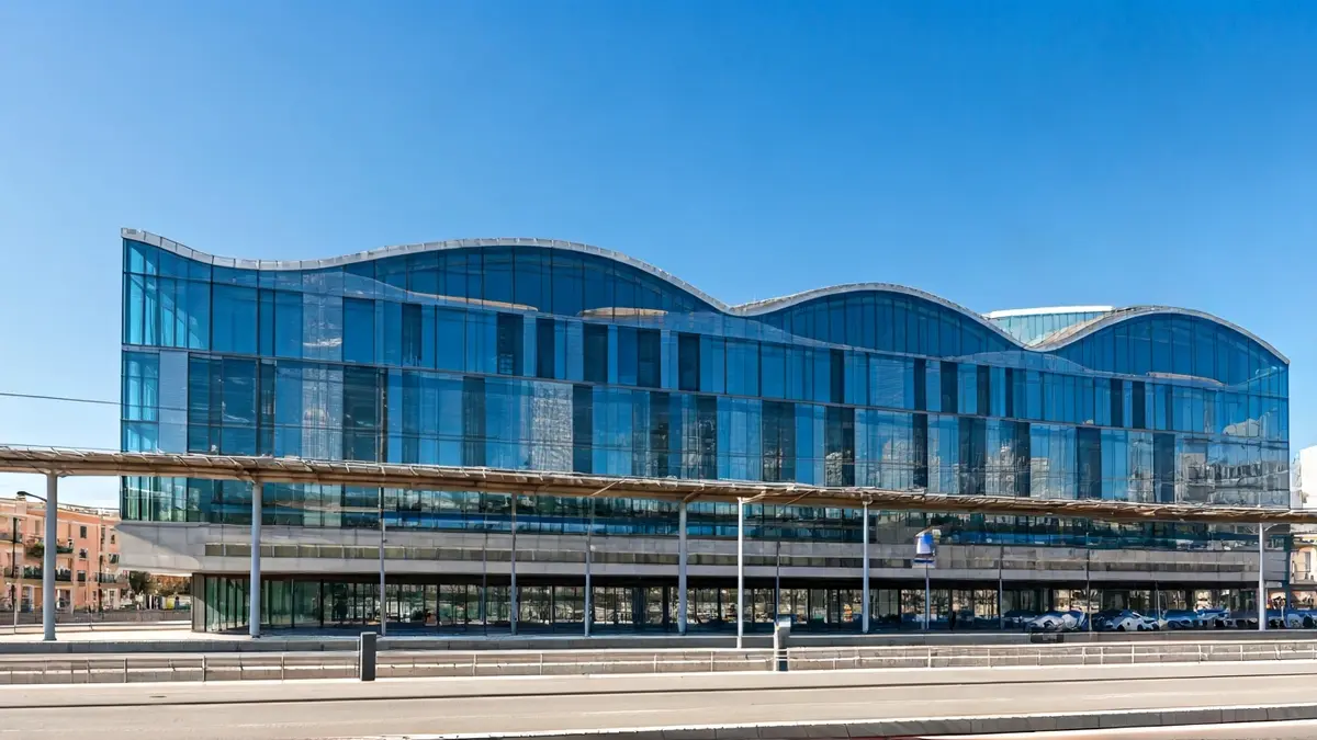 Imatge d'un edifici modern i avantguardista, amb grans finestrals, prop d'una estació de tren.