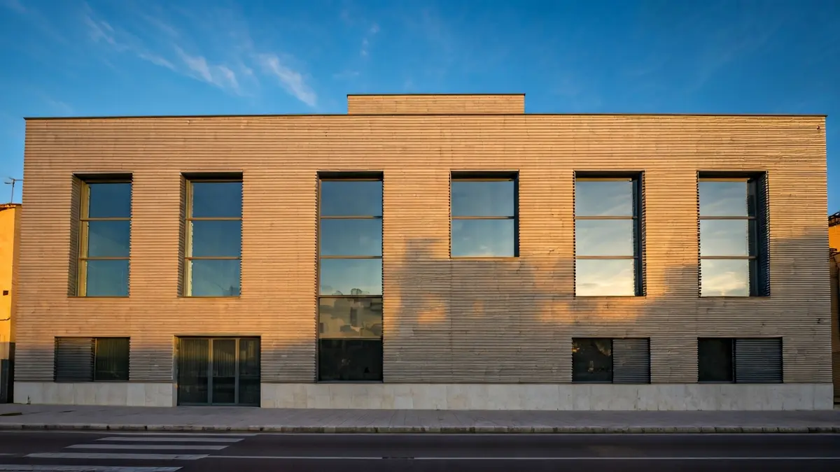 Imatge d'un edifici modern i rehabilitat, amb grans finestrals, en un entorn urbà mediterrani.