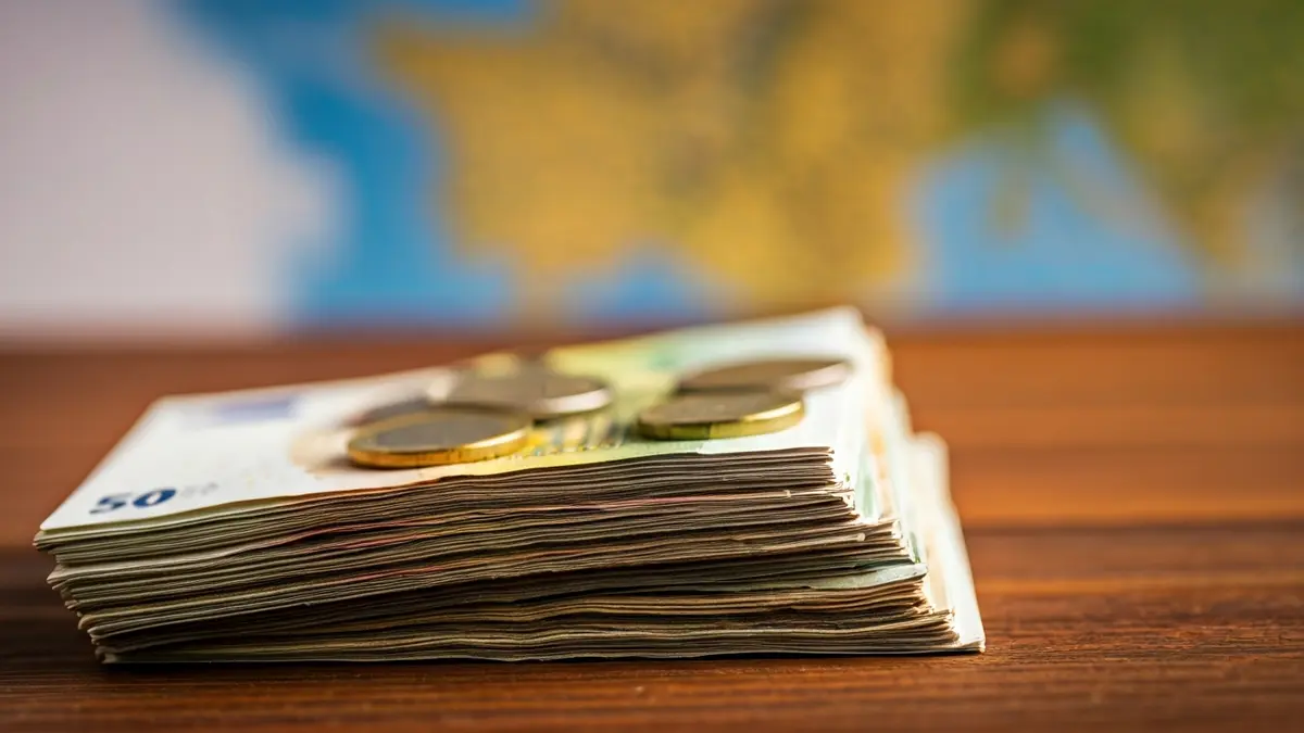 Imagen genérica de dinero en efectivo y un mapa de la Comunitat Valenciana, simbolizando el impacto económico del turismo.