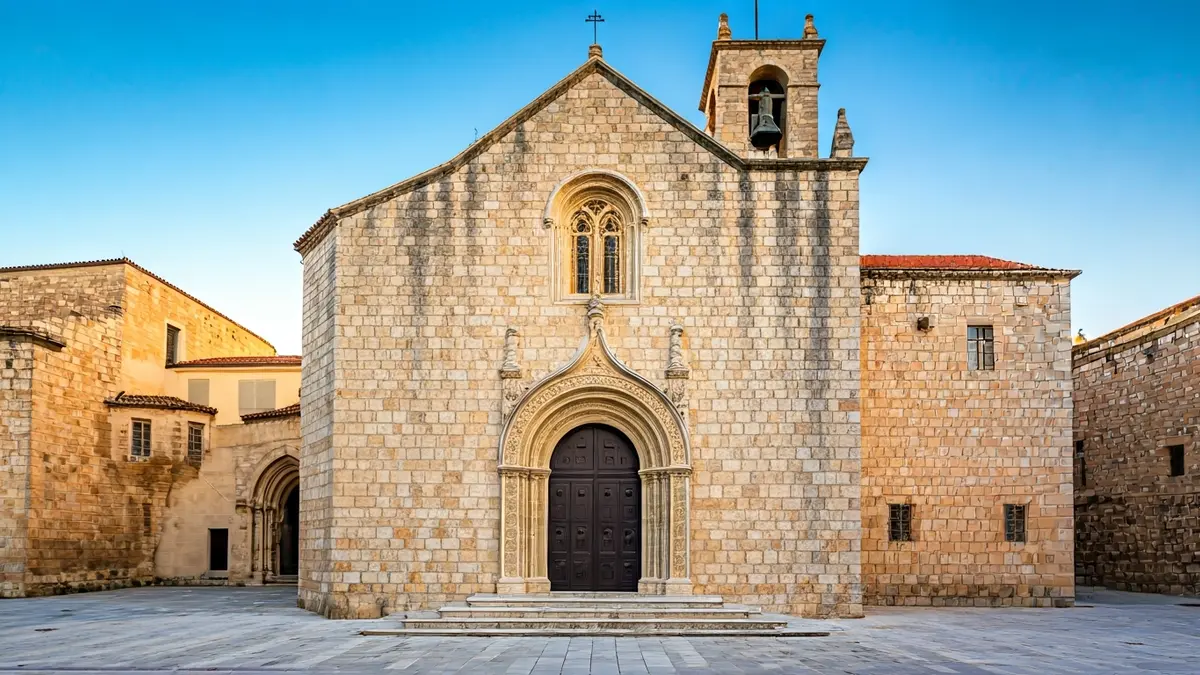 Façana de pedra d'un monestir mediterrani amb detalls arquitectònics, il·luminada pel sol de la vesprada.
