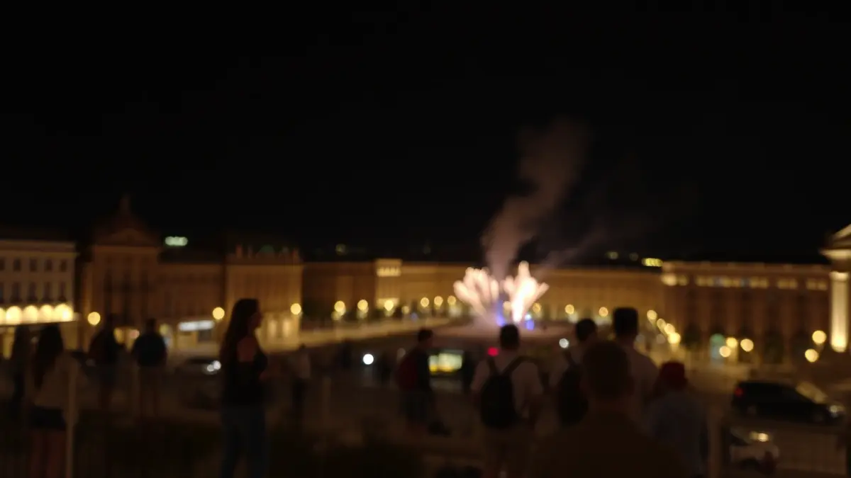 Imagen de una mascletà nocturna en una plaza de València, con luces borrosas y humo.