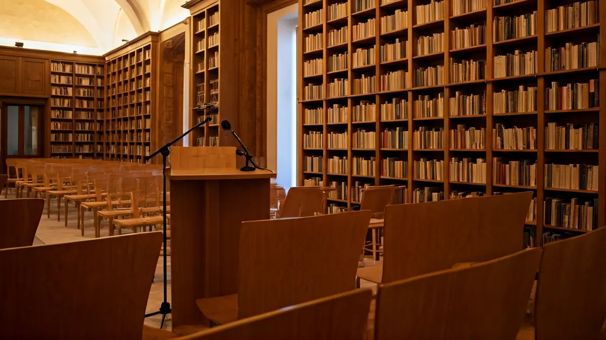 Generic image of a presentation room or library with a podium and empty chairs, warm lighting.