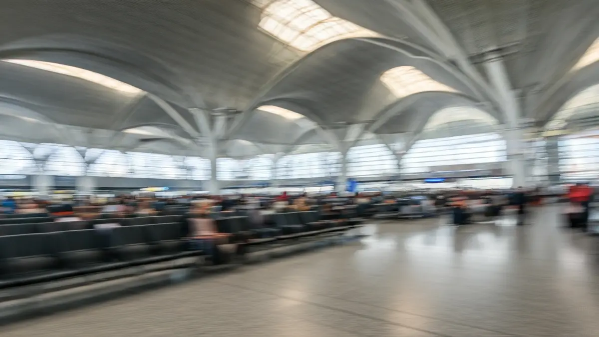 Generic image of an airport terminal interior with blurred passengers and natural light.