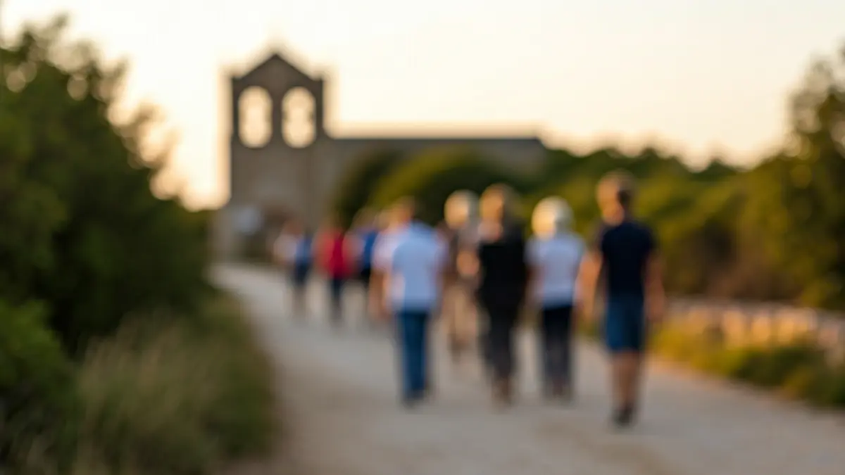 Imagen de un grupo de peregrinos caminando hacia una ermita al atardecer.