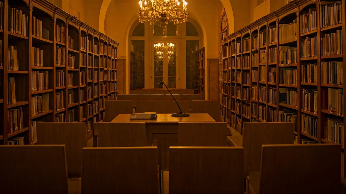 Imagen genérica de un interior de biblioteca con un podio y micrófono, con una atmósfera cálida de lectura.