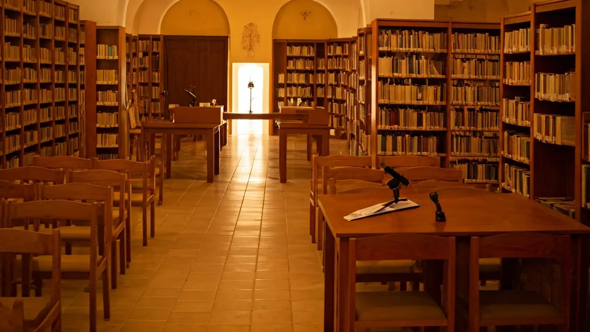 Imatge genèrica d'una biblioteca amb prestatgeries de fusta i un faristol amb micròfon.