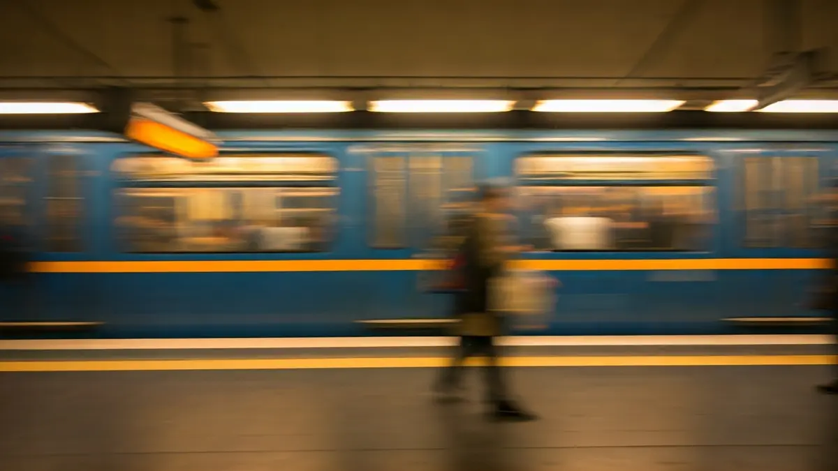Generic image of a metro train arriving at a station, with warm lights and blurred figures.