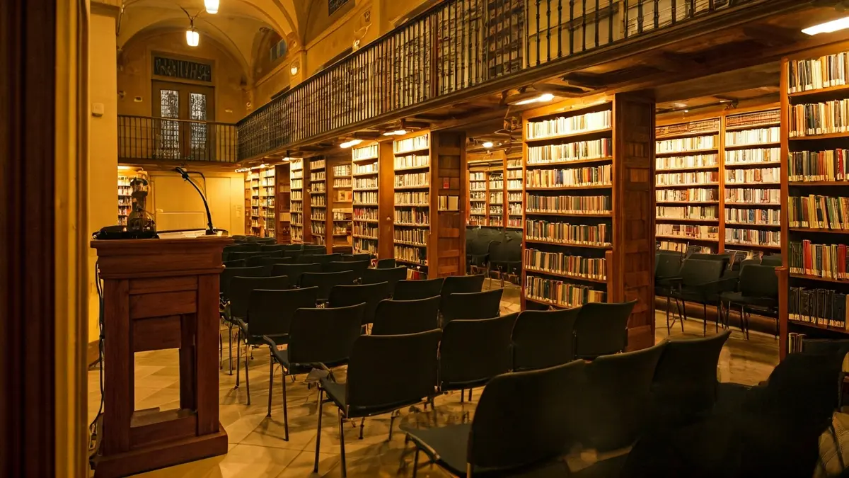 Generic image of a library with wooden bookshelves and a podium with a microphone.
