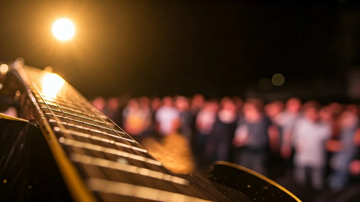 Imatge genèrica d'una guitarra elèctrica en un escenari, amb llums càlides i públic difuminat.