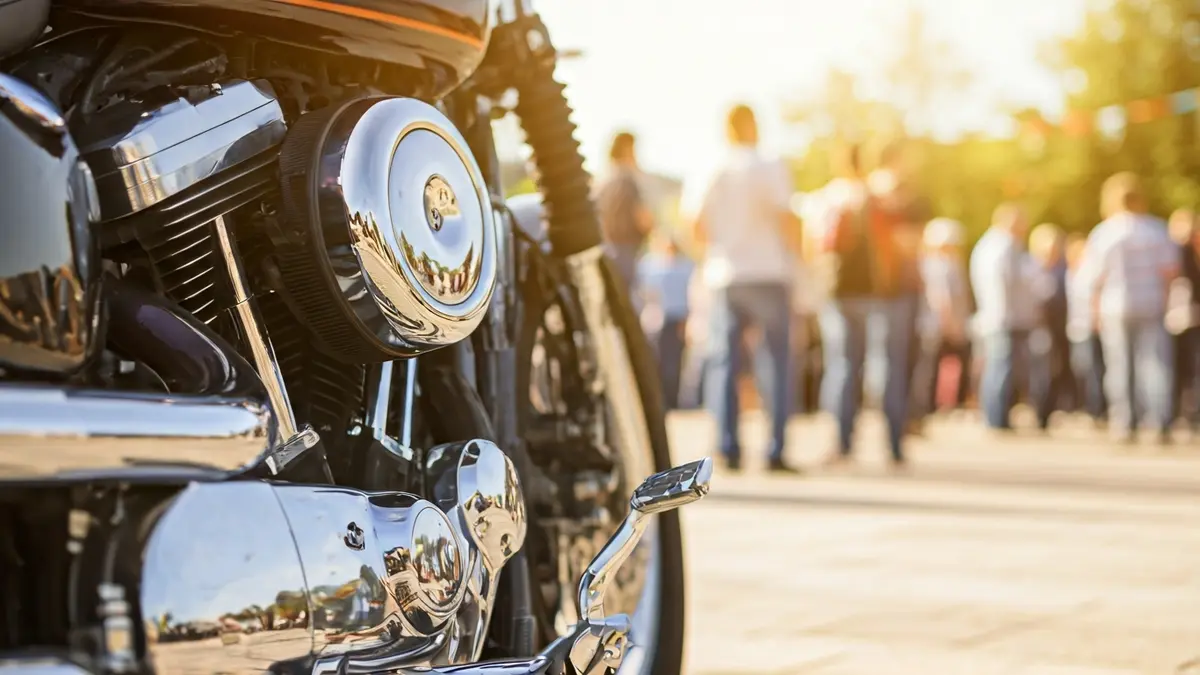 Imatge d'un motor de motocicleta amb detalls cromats, amb un fons desenfocat d'una trobada festiva.