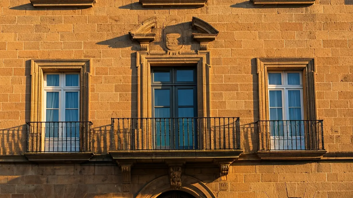 Façana de l'ajuntament de Novelda amb balcons de ferro forjat i llum solar càlida.