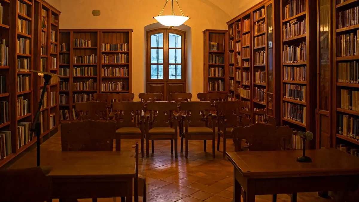 Imagen genérica de un interior de biblioteca con estanterías de madera y un podio con micrófono.