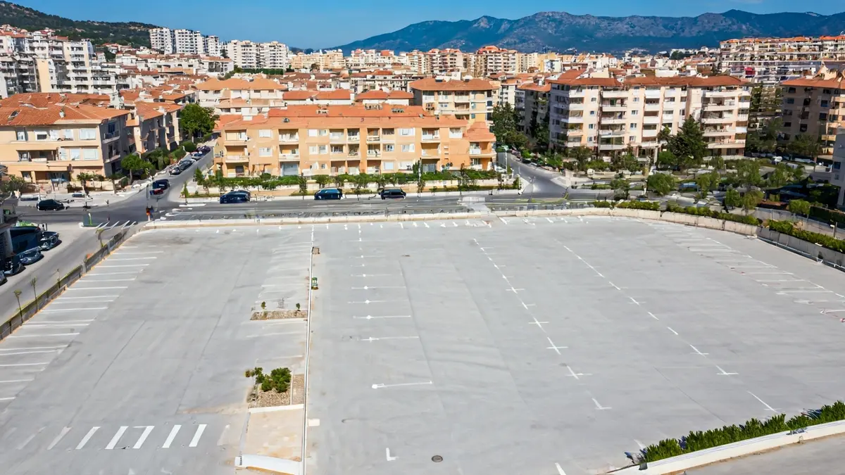 Imatge aèria d'un aparcament nou en una zona urbana mediterrània.