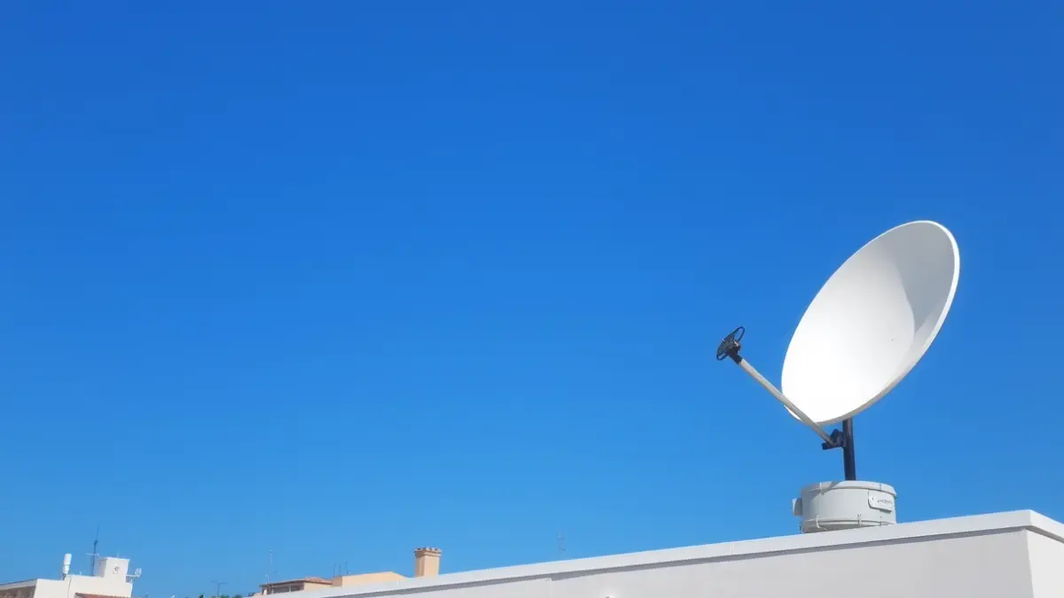 Imagen de una antena satelital en el tejado de un edificio municipal, con un cielo azul claro, simbolizando la comunicación y la seguridad.