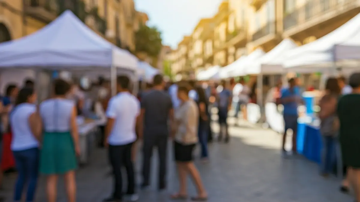 Generic image of an educational street fair in a Mediterranean town, with booths and a central tent, people interacting, warm daylight.