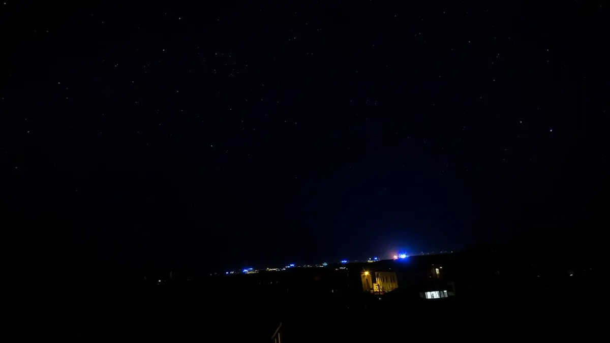Generic image of a star-filled night sky over a Mediterranean city with distant blue emergency lights.
