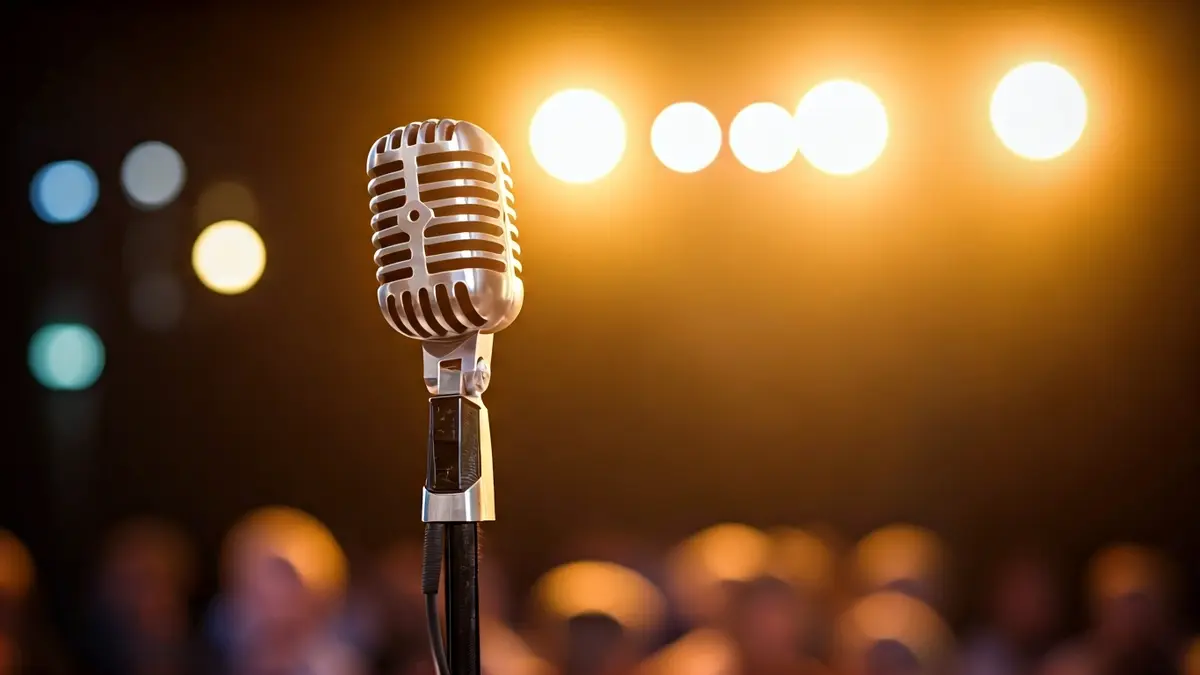 Generic image of a vintage microphone on a stage, with blurred spotlights in the background.