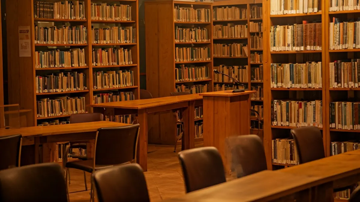 Imatge genèrica d'una biblioteca amb prestatgeries de fusta i un faristol amb micròfon.