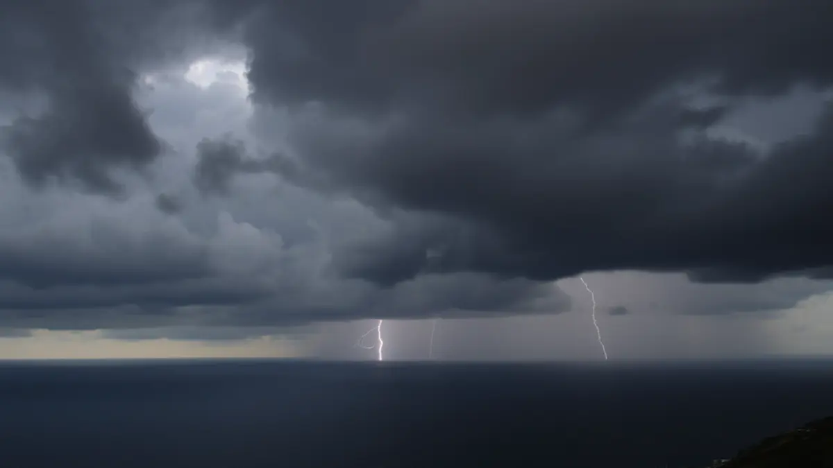 Imatge genèrica de núvols de tempesta foscos sobre un paisatge costaner mediterrani amb pluja intensa.