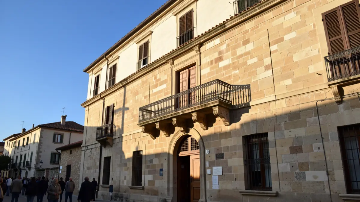 Generic image of a Mediterranean town hall with a balcony and warm lighting.