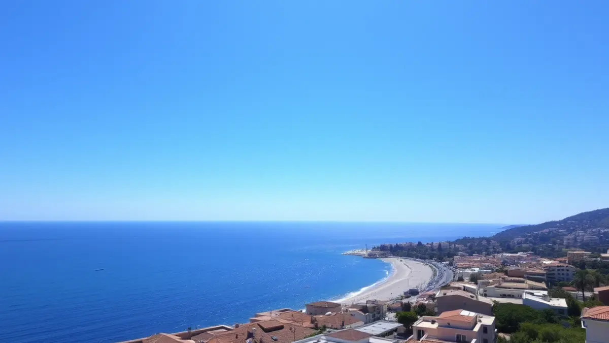 Imatge genèrica d'un cel clar sobre una ciutat costanera mediterrània, amb una platja de sorra i mar en calma.