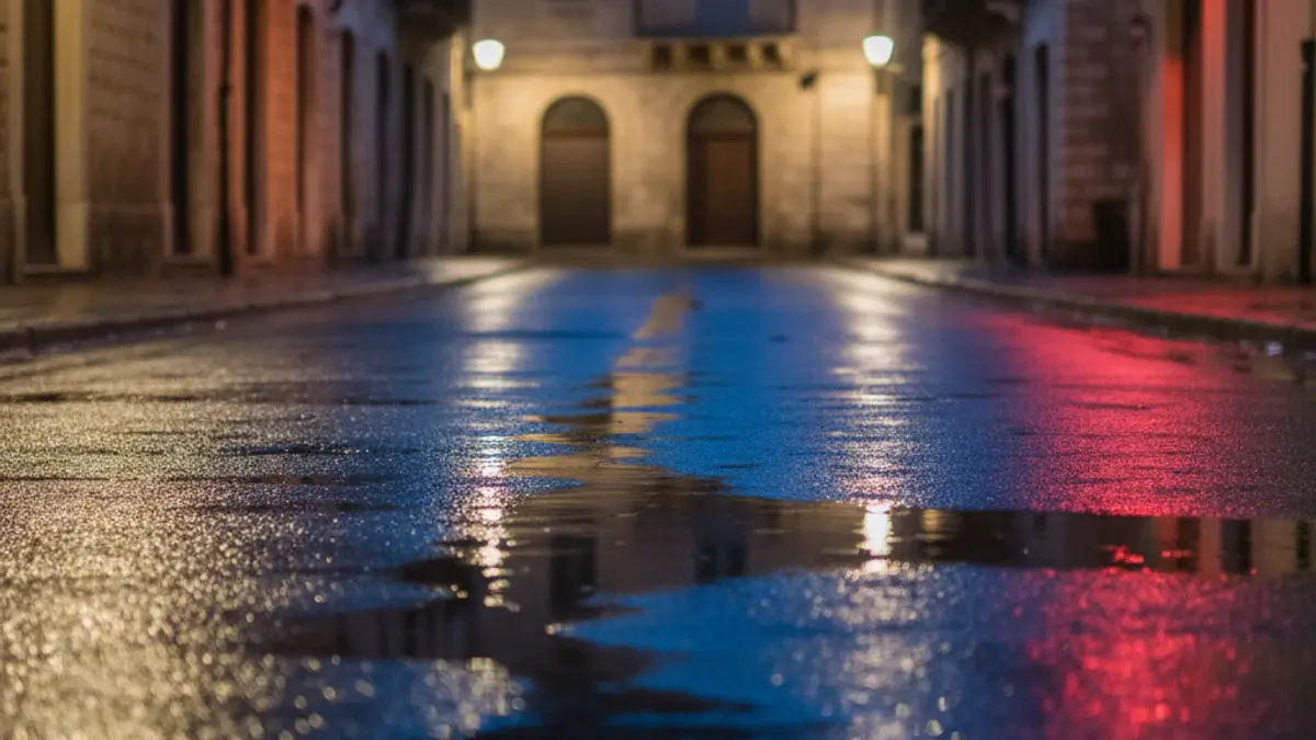 Imagen genérica de luces de emergencia reflejándose en el asfalto mojado de noche.