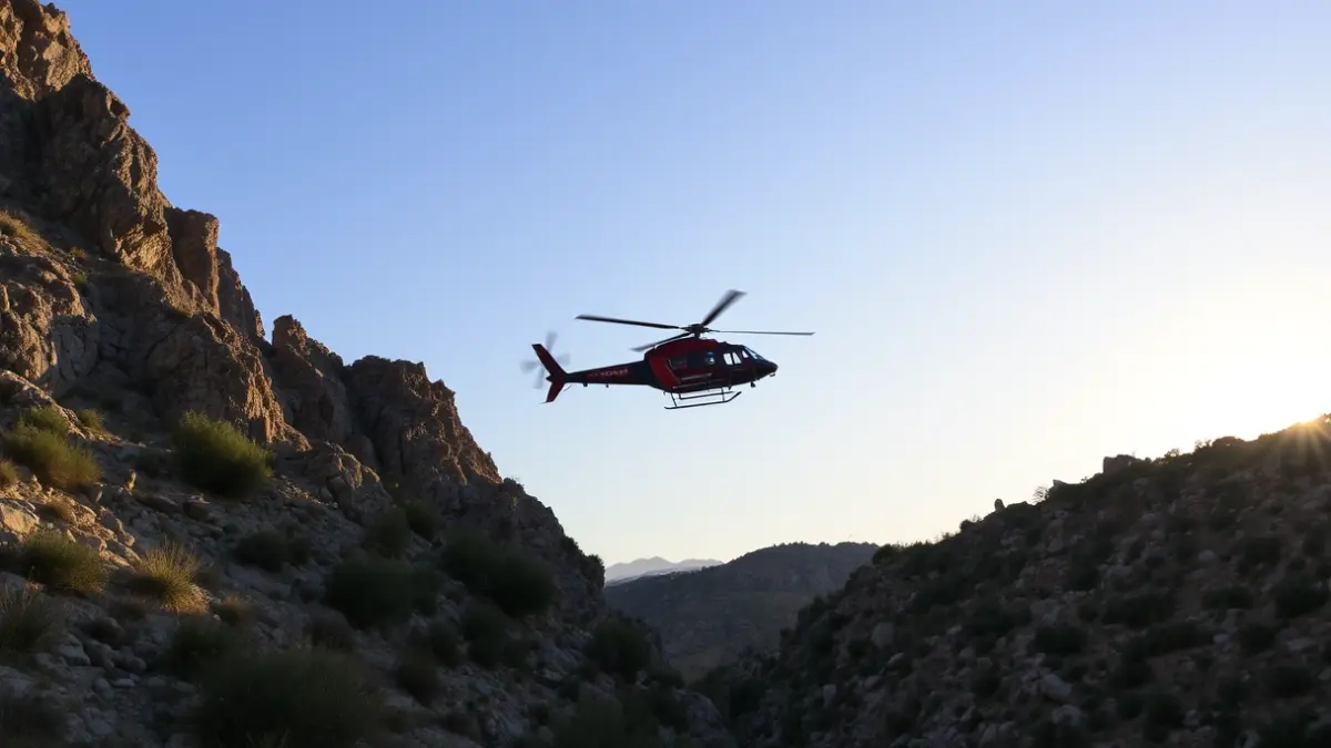 Image of a rescue helicopter flying over a rocky ravine in a Mediterranean area.