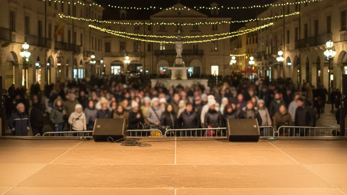 Generic image of an empty stage in a town square at night, with blurred lights, before a performance.