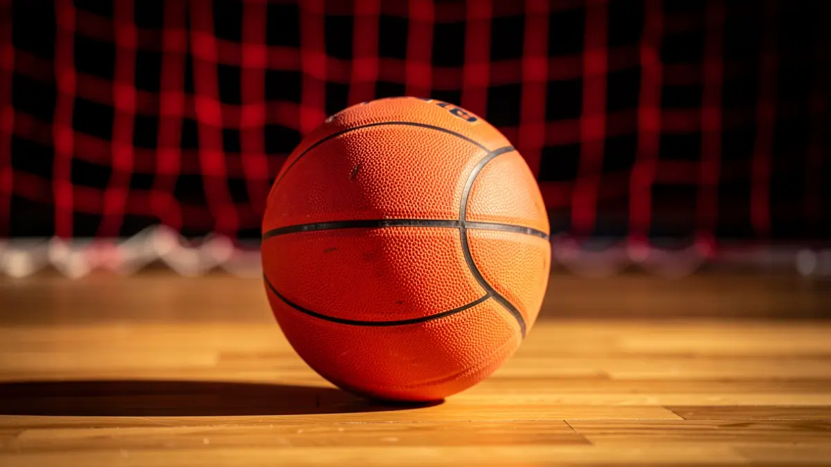 Balón de baloncesto sobre una pista de madera, con los colores rojo y negro del CB Puerto.