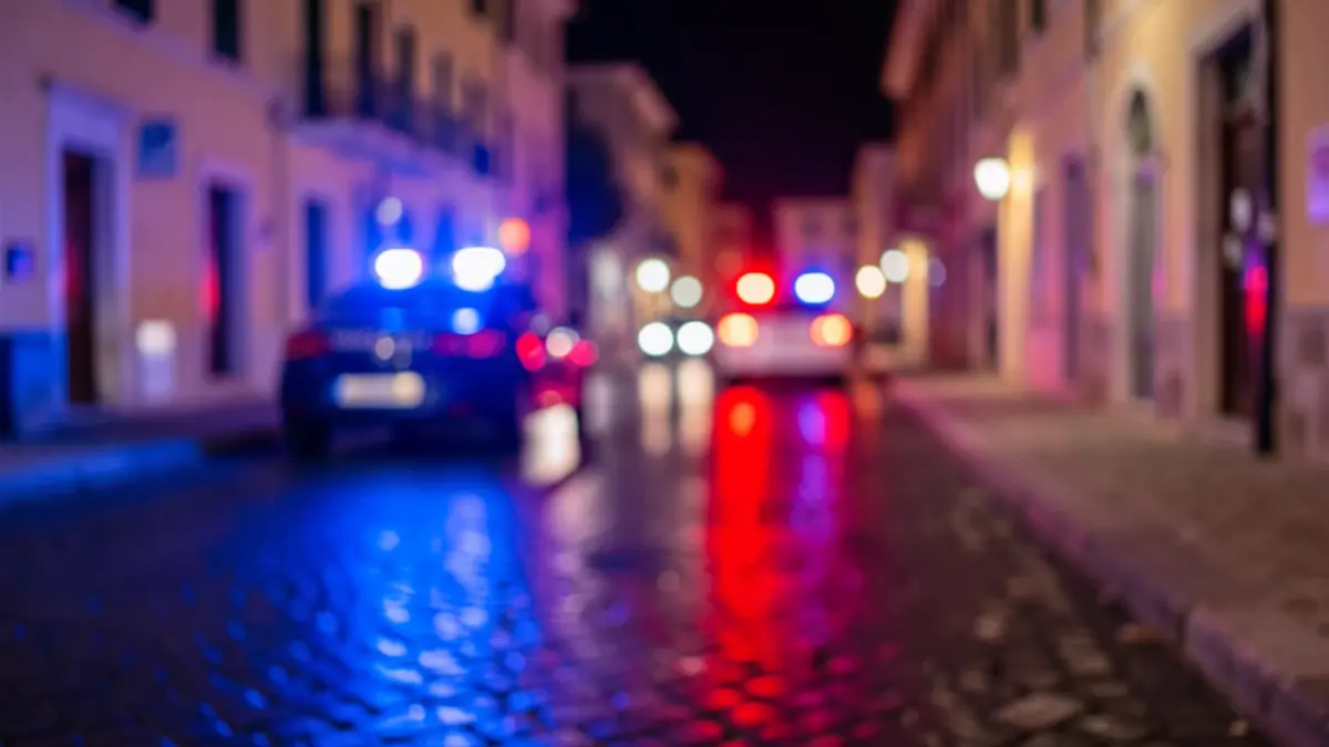 Imagen genérica de luces de emergencia policiales reflejándose en asfalto mojado.
