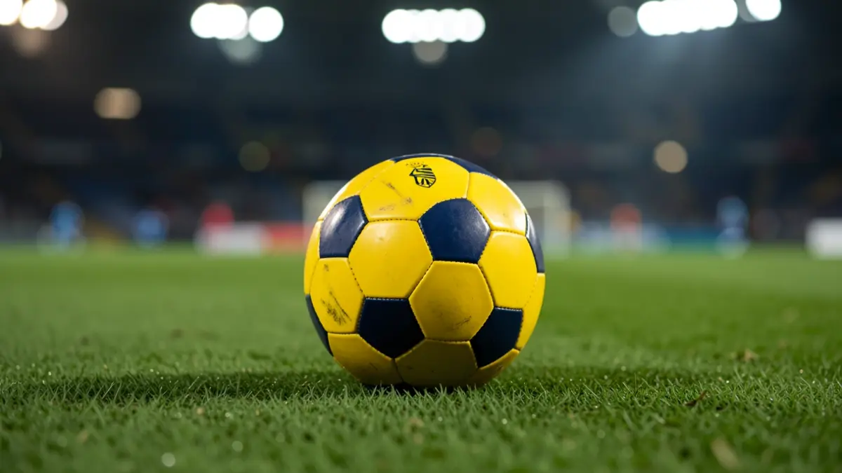 Generic image of a soccer ball on grass with stadium lights in the background.